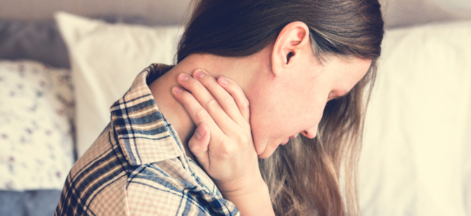 Femme qui se tient la nuque à cause de douleurs