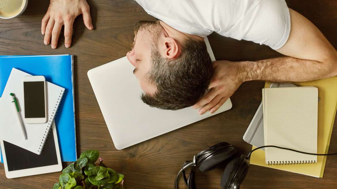 Homme affalé sur le bureau de travail